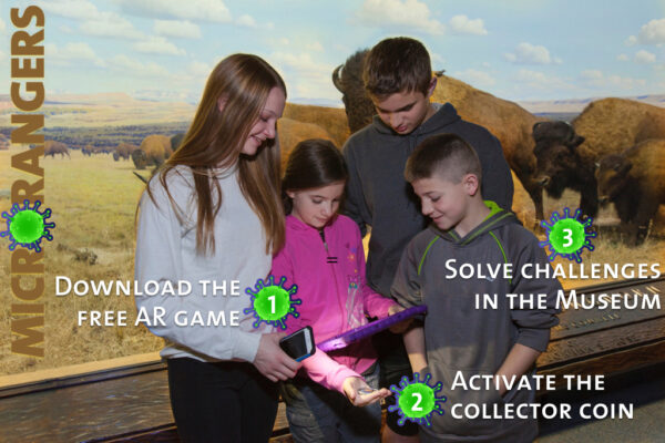 4 children in front of a museum exhibit with a mobile device. 